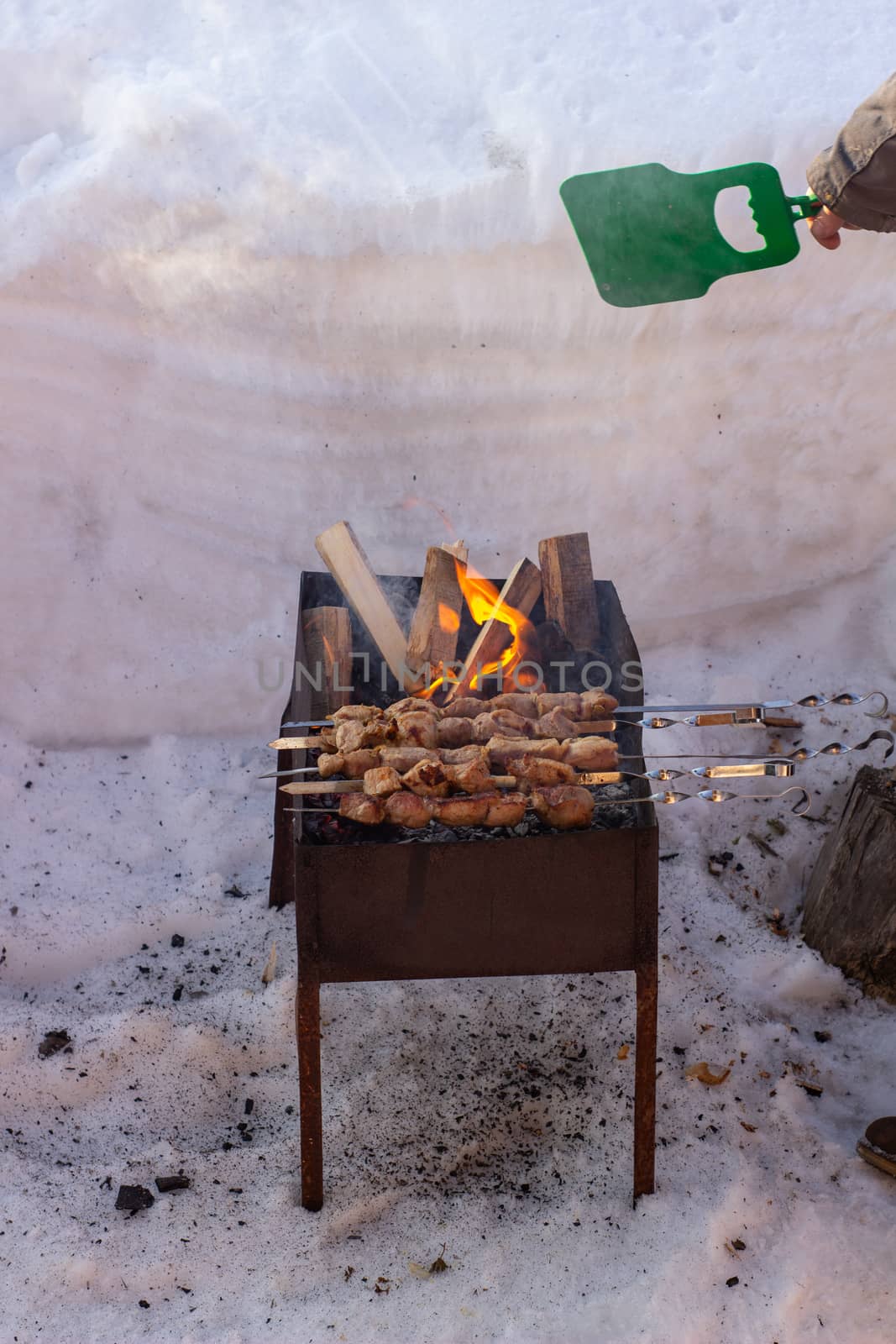 Cooking meat on the fire. Shish kebab on the grill. The grill is lit outside in winter. Fry shish kebabs on the grill