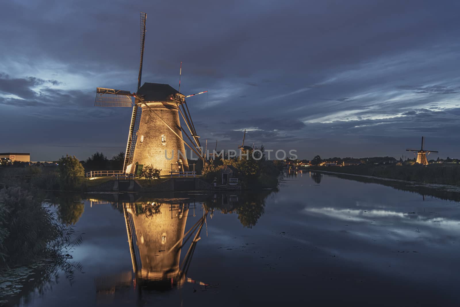 Illuminated windmill reflected on the calm canal water during the bleu hour sunset in Alblasserdam city, Netherlands