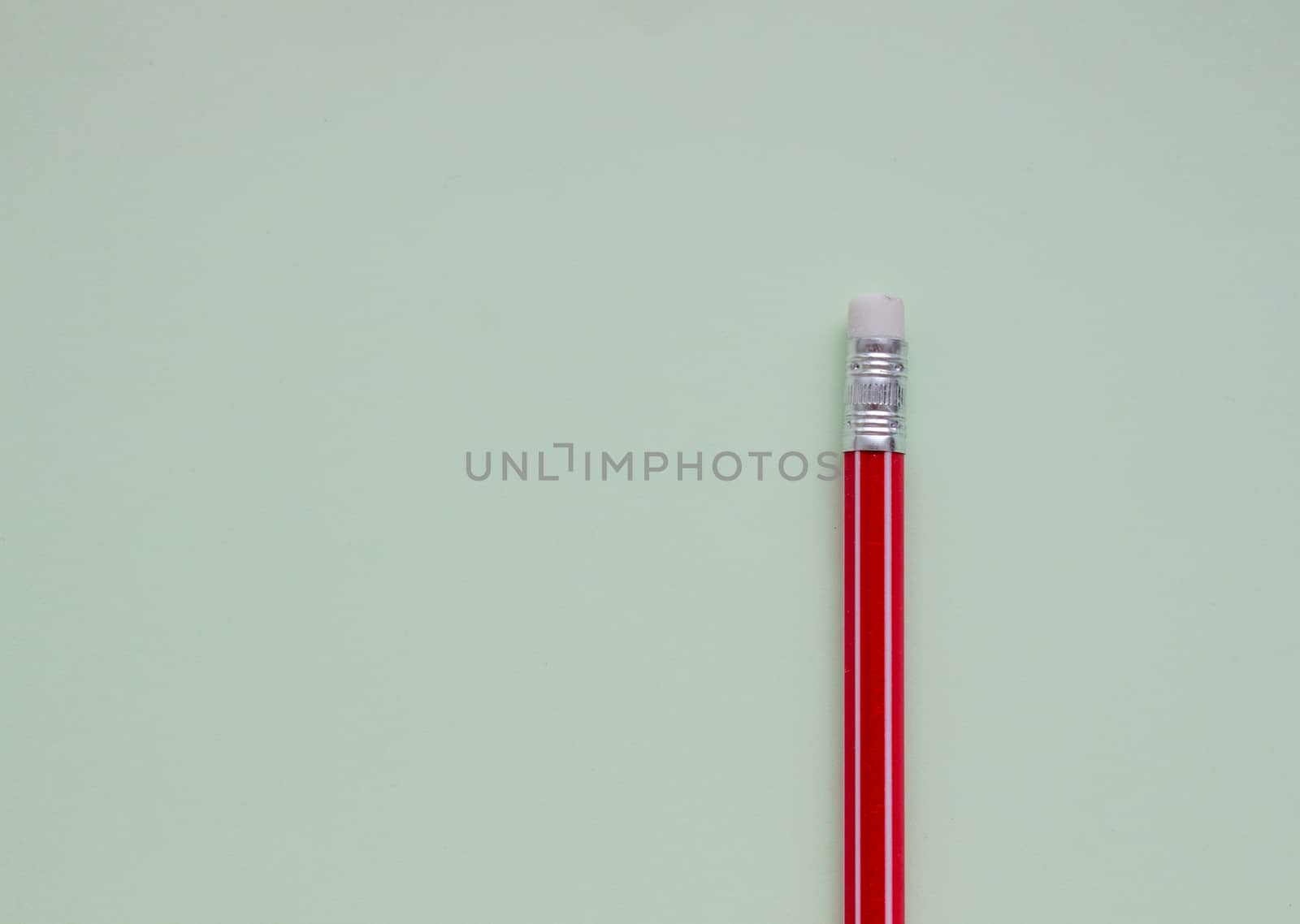 One red pencil on a light green background. by AnatoliiFoto