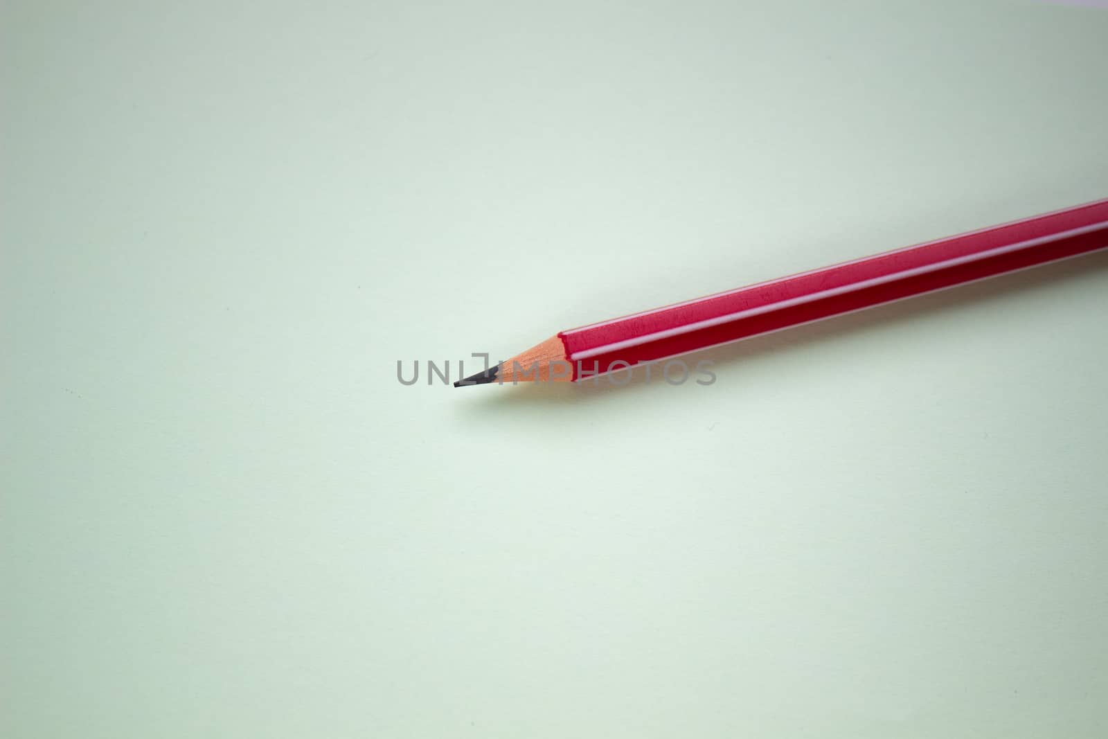 One red pencil on a light green background