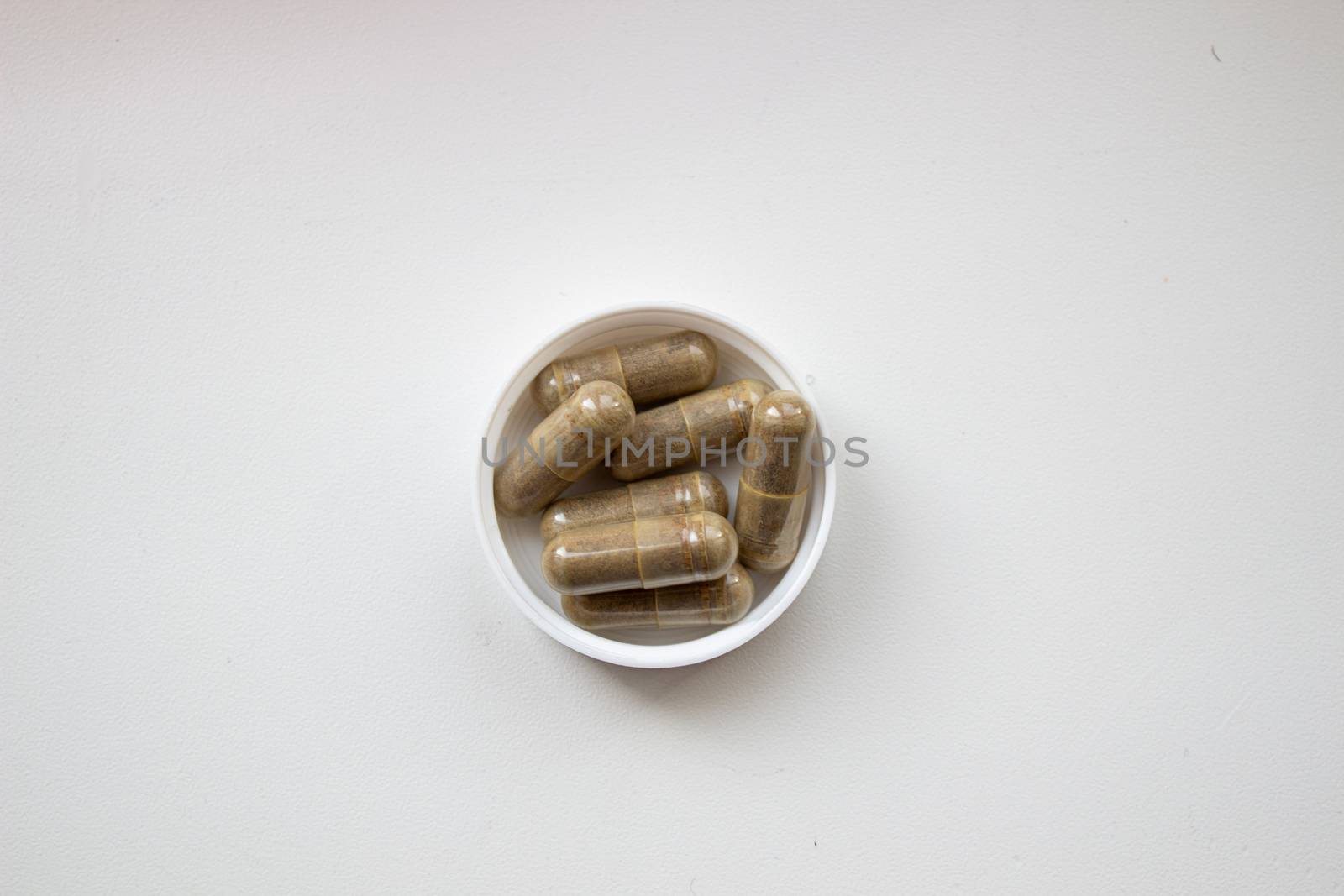Herbal capsule and powder on white background