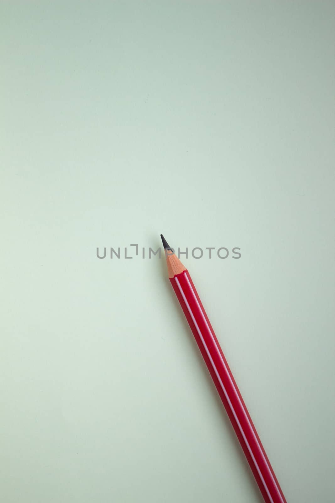 One red pencil on a light green background