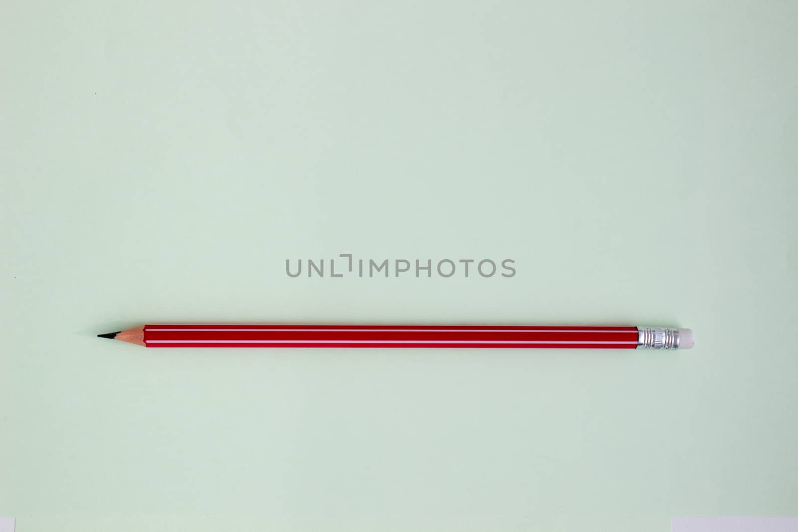 One red pencil on a light green background. by AnatoliiFoto