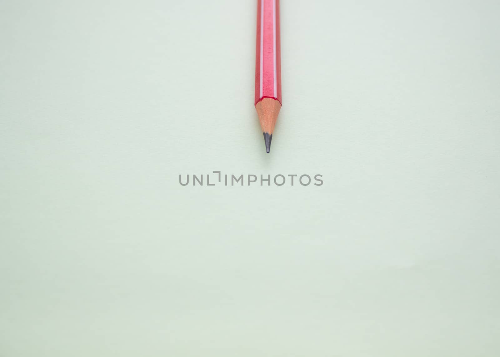 One red pencil on a light green background