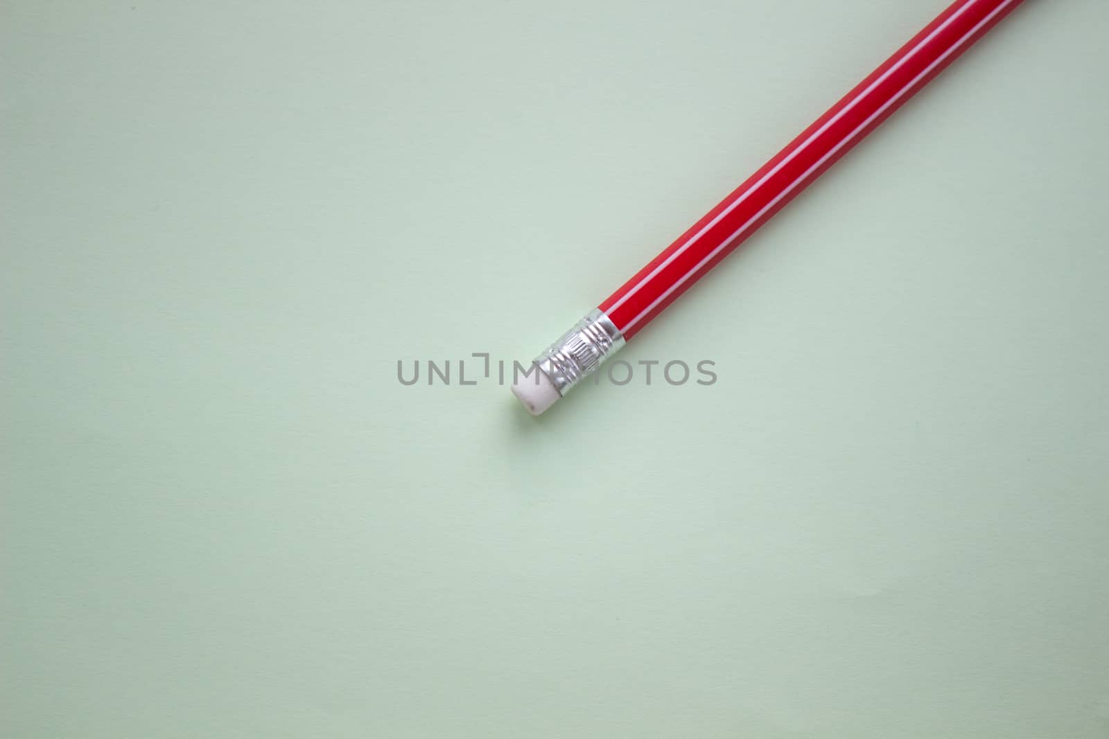 One red pencil on a light green background