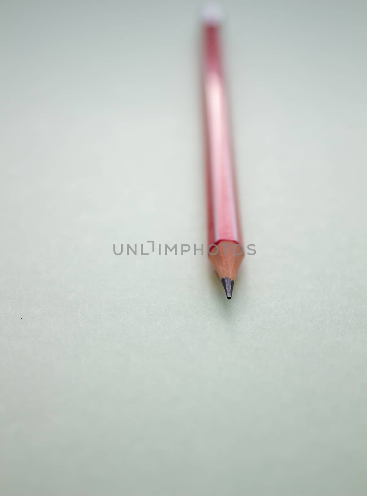 One red pencil on a light green background