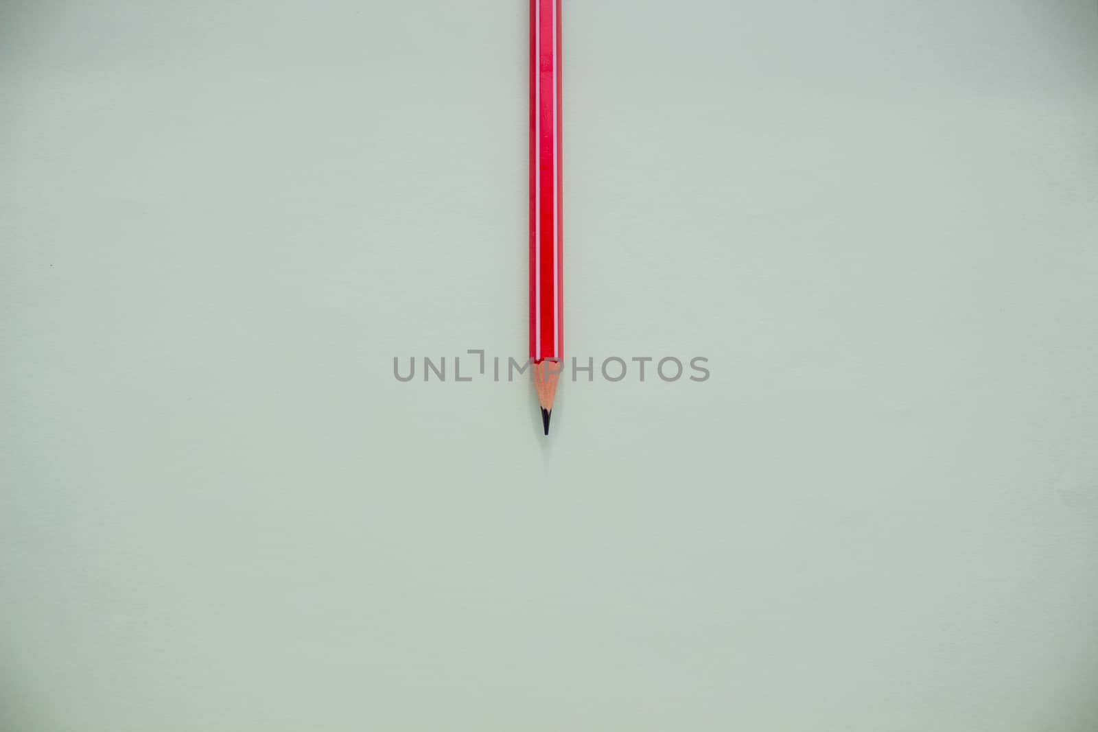 One red pencil on a light green background