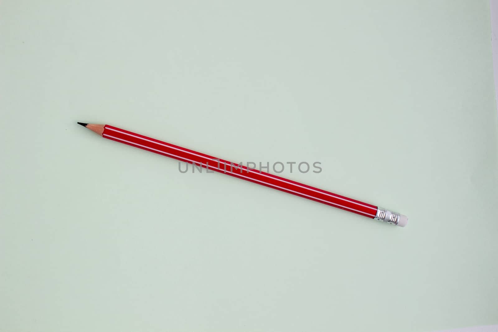 One red pencil on a light green background