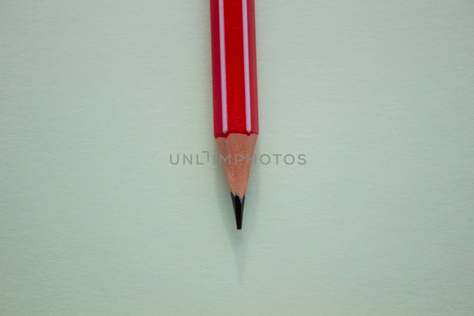 One red pencil on a light green background