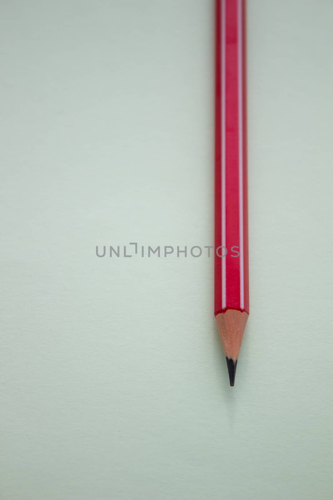 One red pencil on a light green background