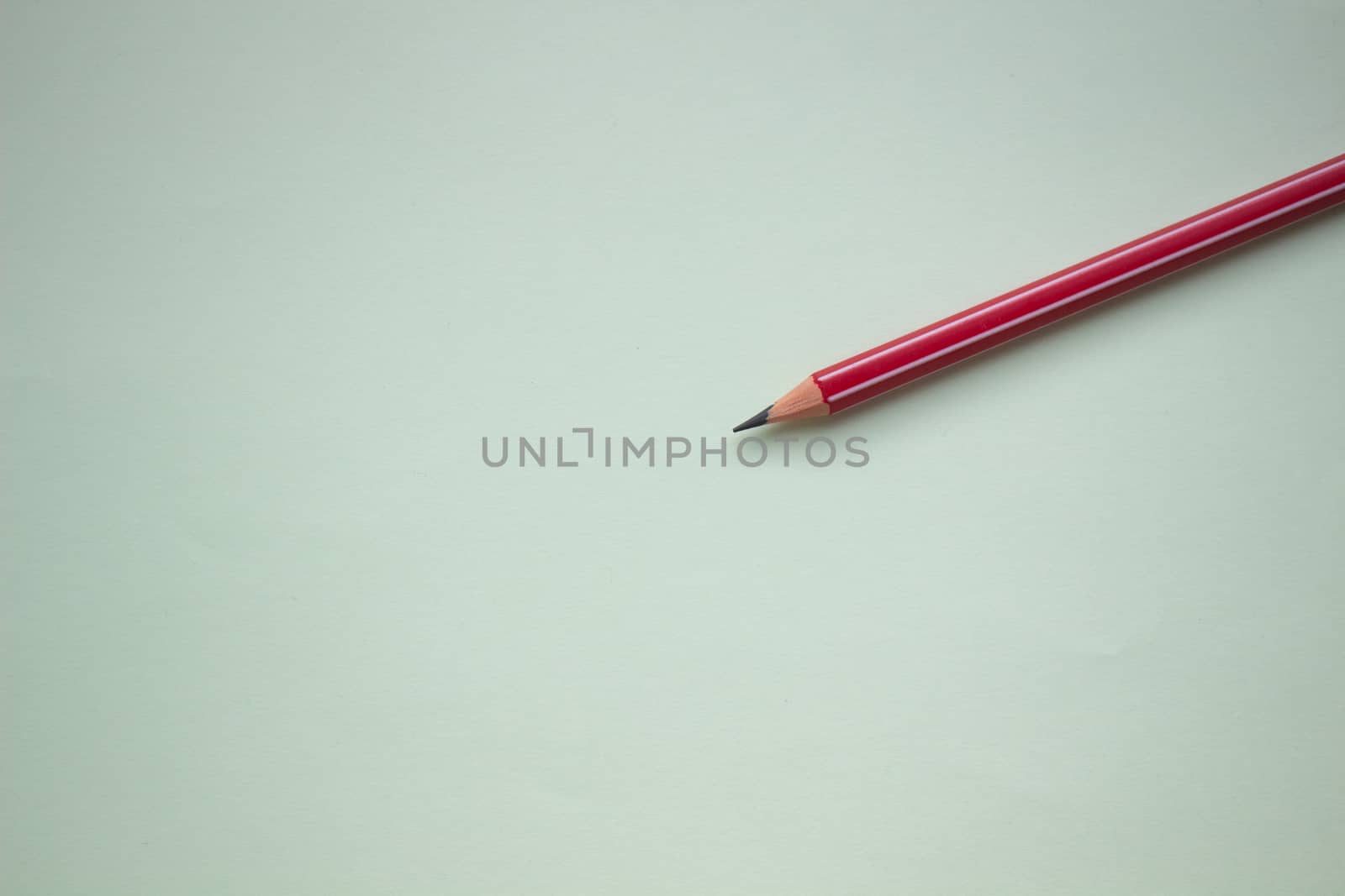 One red pencil on a light green background