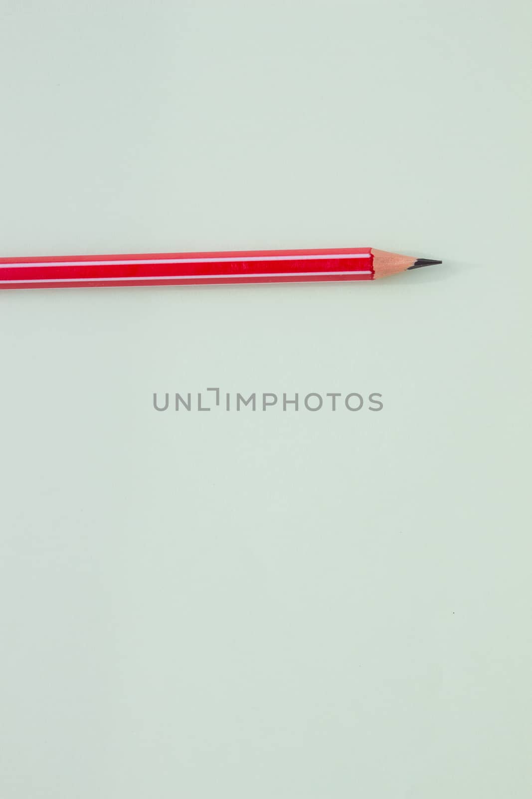 One red pencil on a light green background