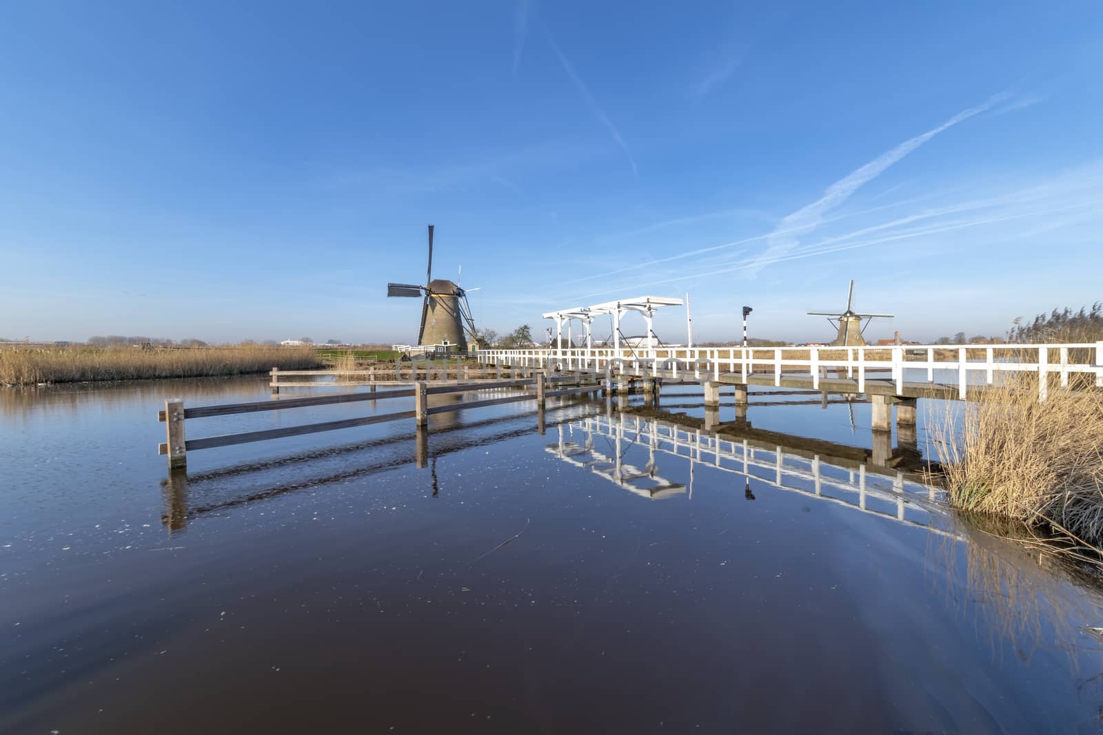 Blue sky Dutch landscape with the windmill over the white bridge above a calm and clear water at the early morning, Netherlands by ankorlight