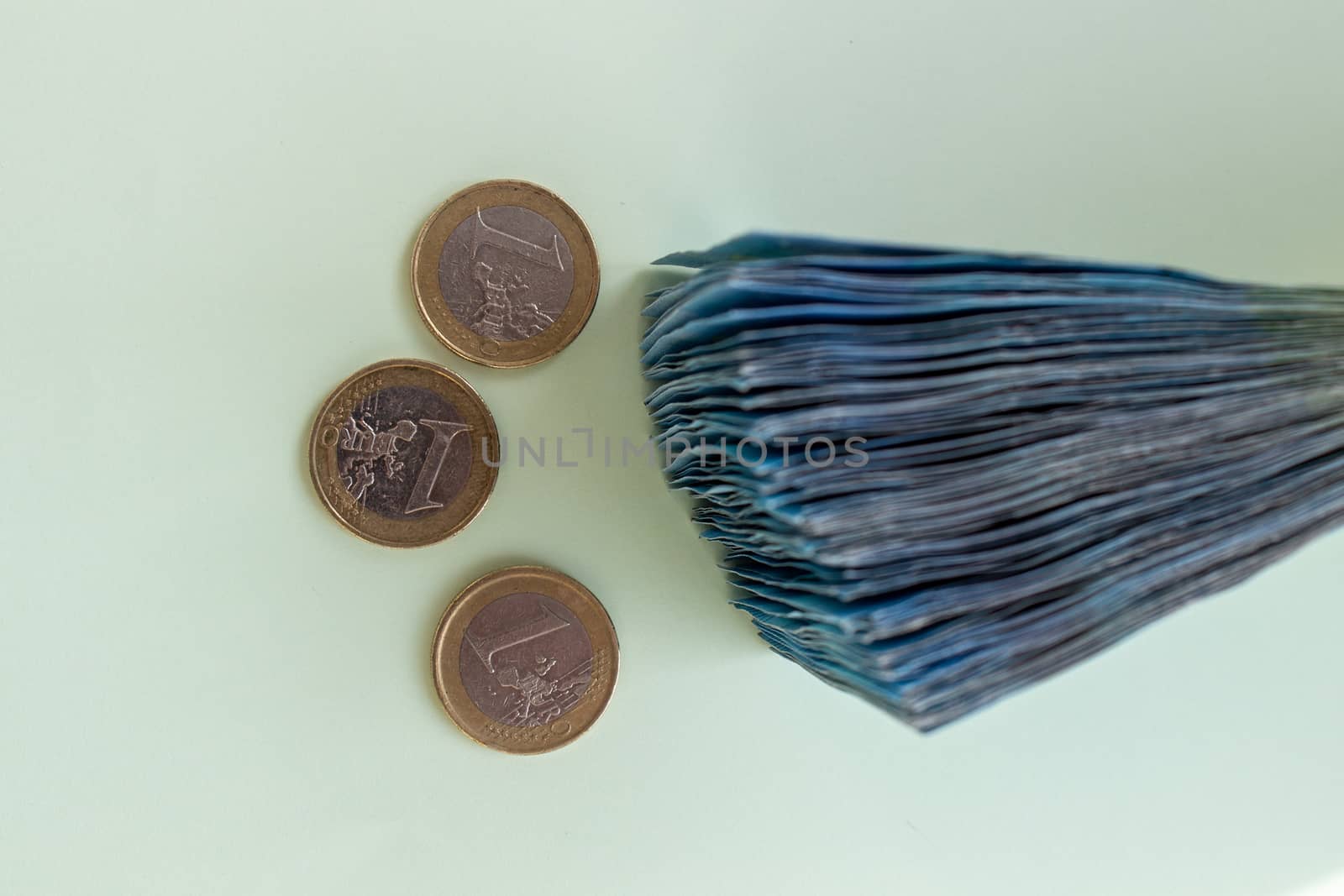 A bundle of 20 Euro banknotes and coins on a light background