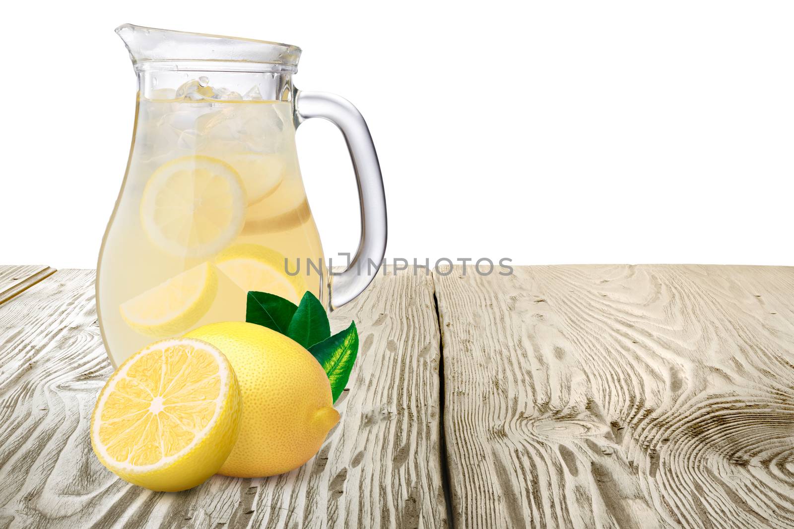 Jug or pitcher of lemonade with lemons on foreground standing on wooden table. Clipping paths for both background and pitcher, infinite depth of field
