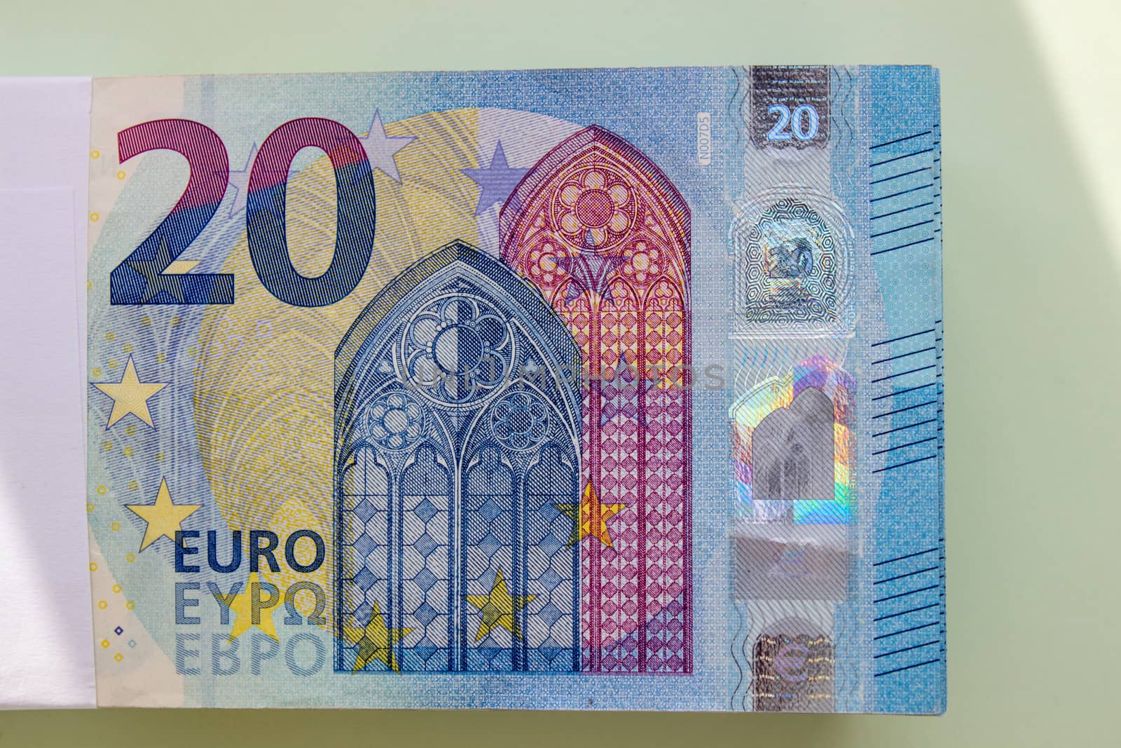 A bundle of 20 Euro banknotes and coins on a light background