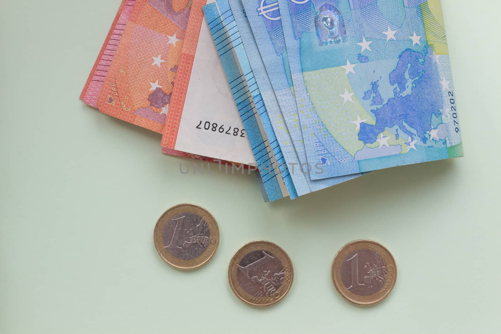 A bundle of 20 Euro banknotes and coins on a light background