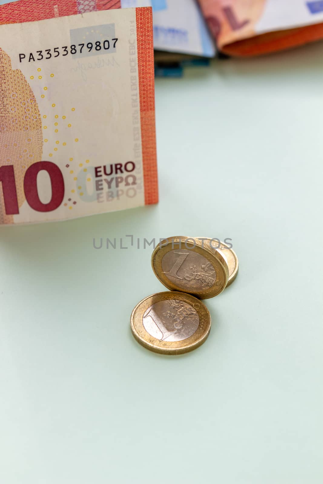 A bundle of 10 Euro banknotes and coins on a light background