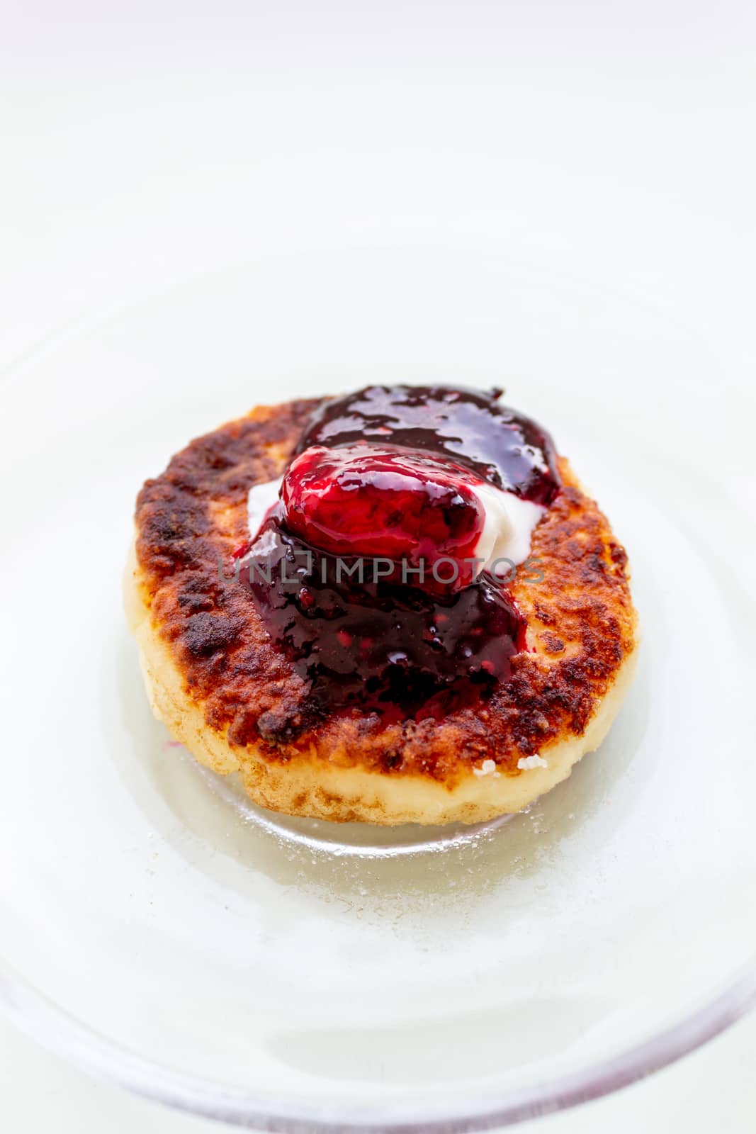 One cheesecake with sour cream and jam on a plate. Healthy breakfast. Cooking from cottage cheese.