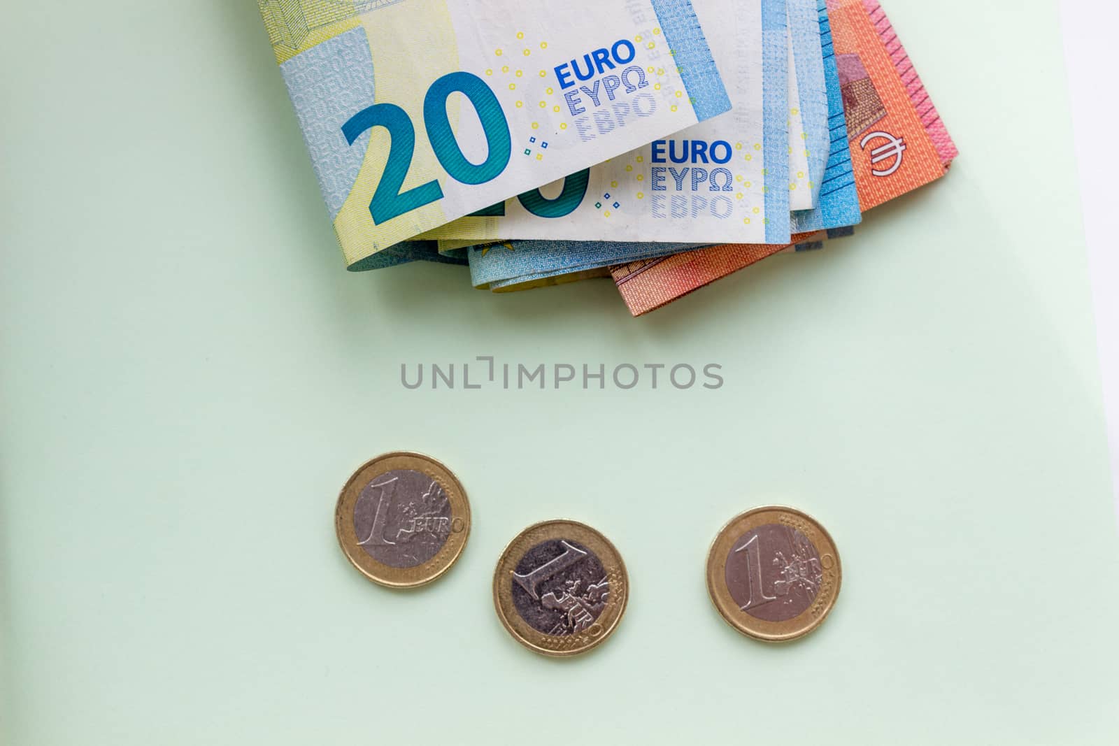 A bundle of 20 Euro banknotes and coins on a light background
