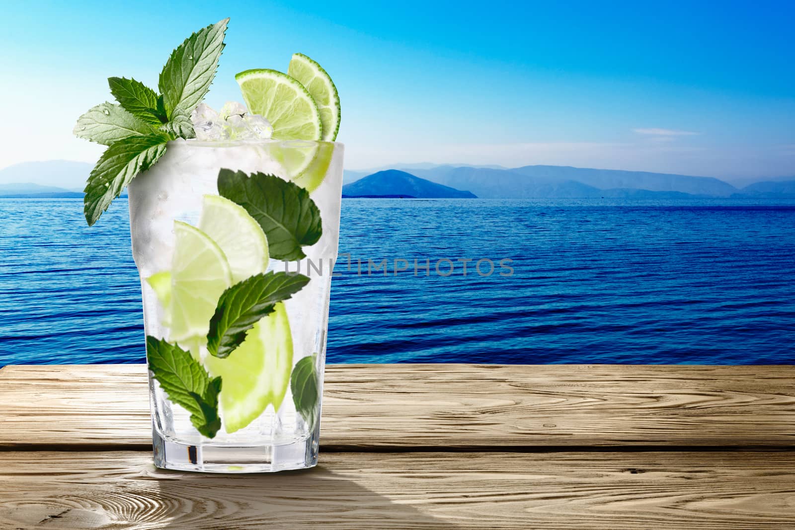 Mojito (alcoholic cocktail with rum, lime and mint)  in wooden table against seascape. Clipping paths, infinite depth of field