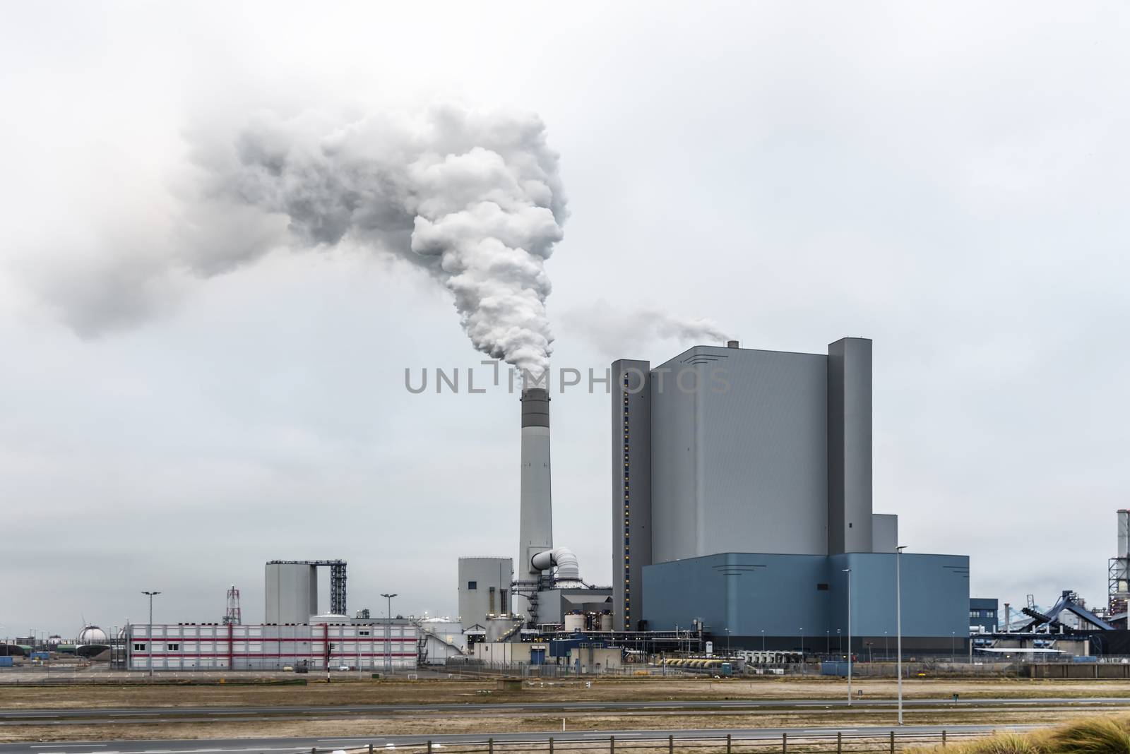 Rotterdam power station splitting chem-tray in the sky through its hight chimney in the industrial area in the Maasvlakte, Netherlands by ankorlight