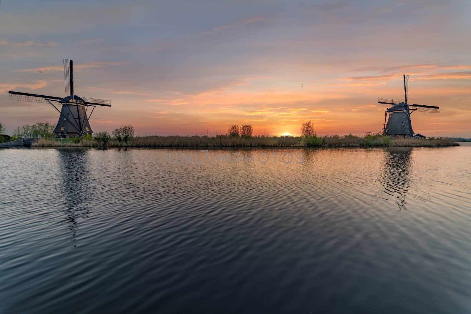 Long exposure of the Kinderdjik windmill sunrise reflection on the calm water of the Alblasserdam canal  by ankorlight