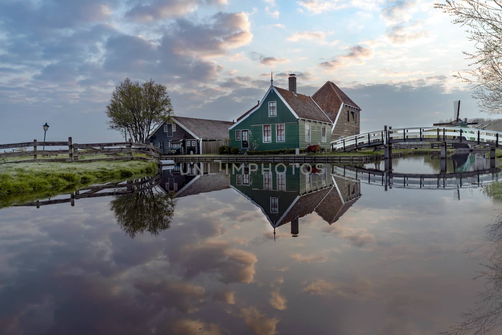 Long exposure of a reflection of the wooden green houses topped with dark orange color roof reflected on the calm water of the canal by ankorlight