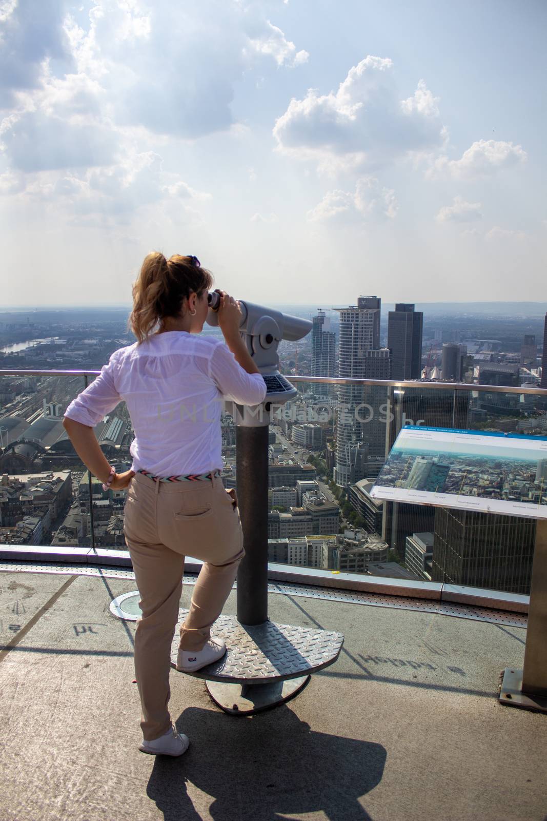 Young tourist girl with looking at the Frankfurt from the top of the main tower. Aerial View Frankfurt am Main from main tower to financial center. by AnatoliiFoto