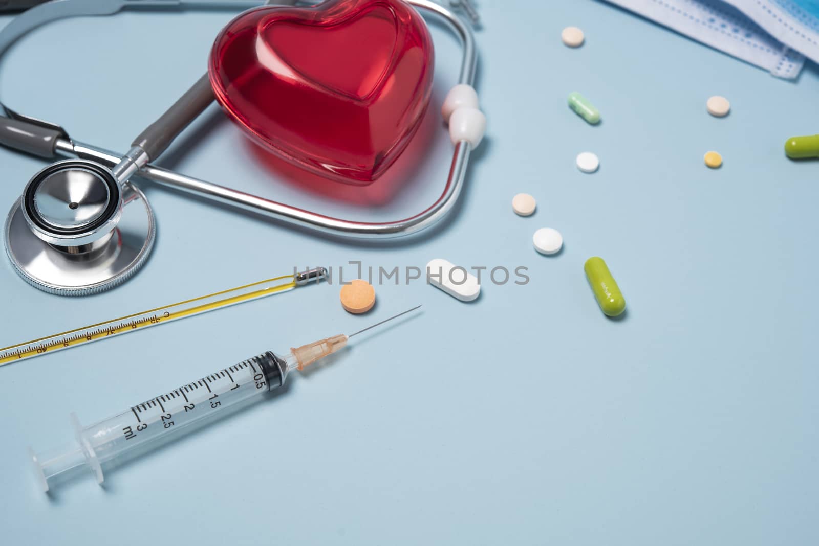 medical equipment stethoscope with red heart and drug, syringe on blue copy space background.