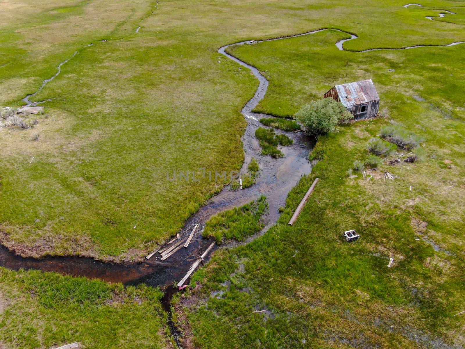 Aerial view of abandoned little wooden house barn next small river in the green valley, Aspen Spring by Bonandbon