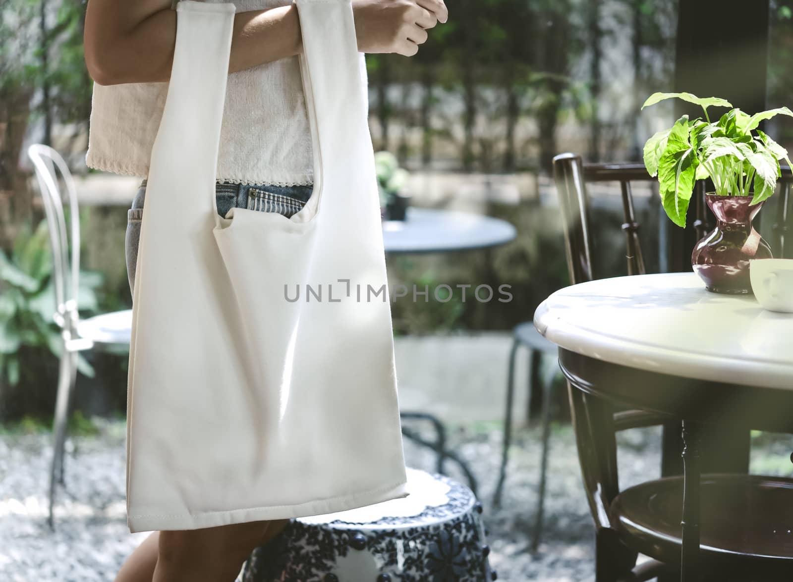 Girl is holding bag canvas fabric for mockup blank template on restaurant background.