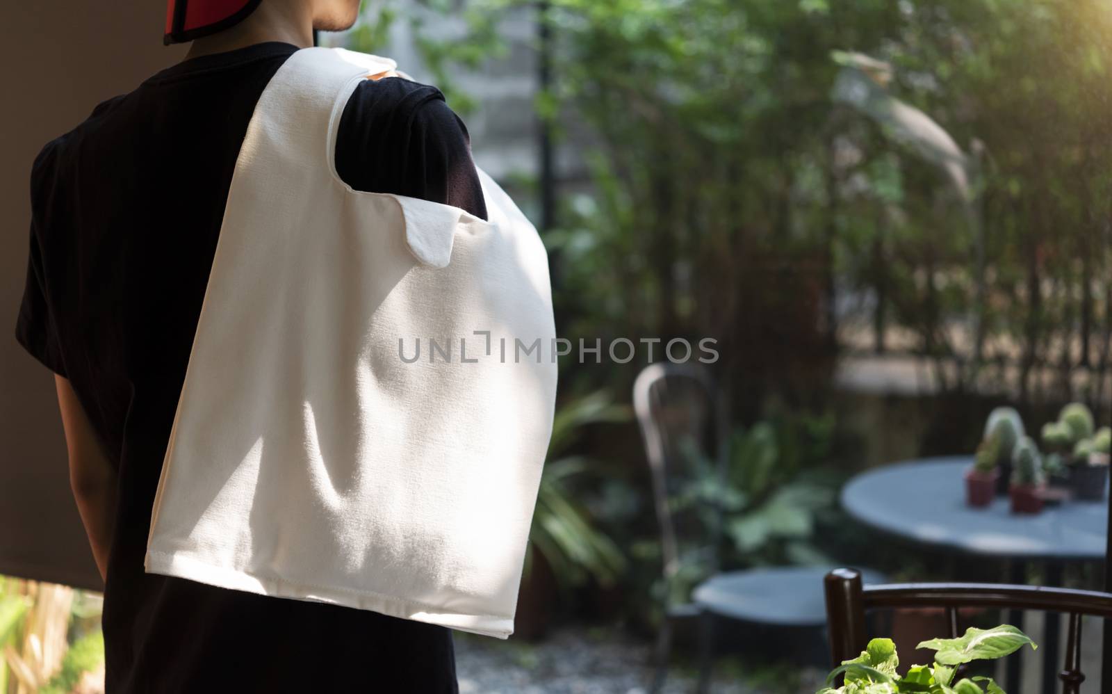 Man is holding bag canvas fabric for mockup blank template on restaurant background.