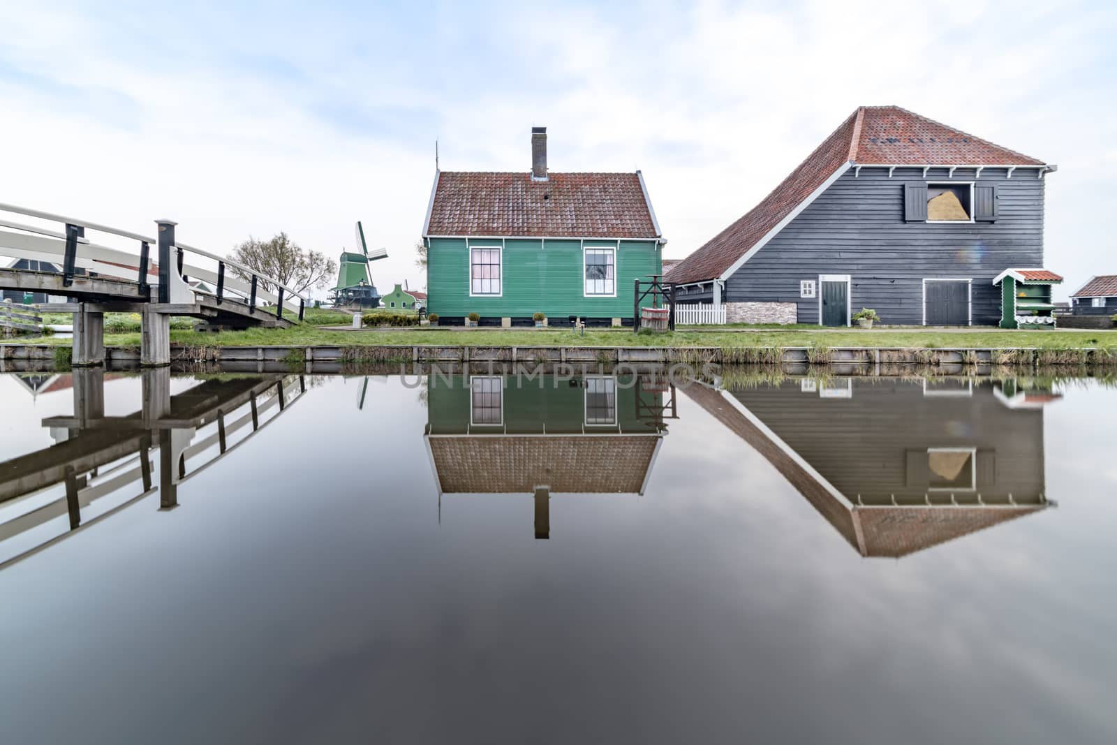 Long exposure of a reflection of the wooden green houses topped with dark orange color roof reflected on the calm water of the canal by ankorlight