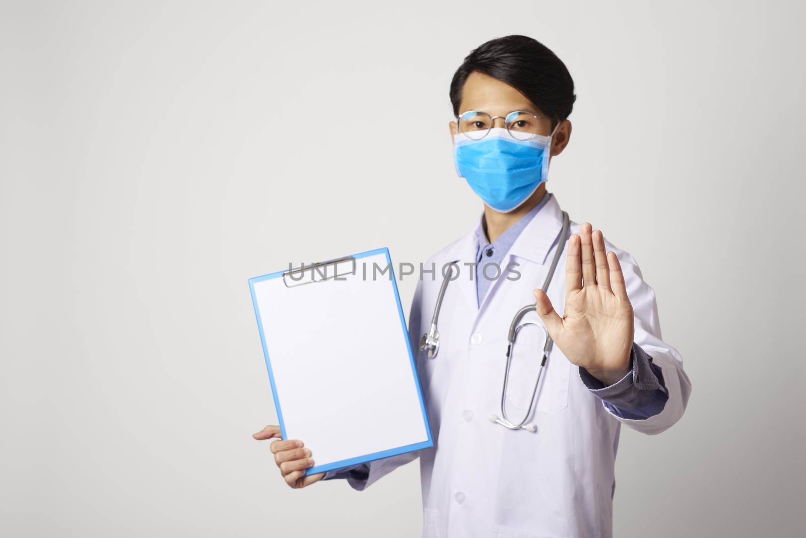 attractive asia man doctor showing stop gesture refusing standing in gray wall background. Concept Preventive measures against corona virus.