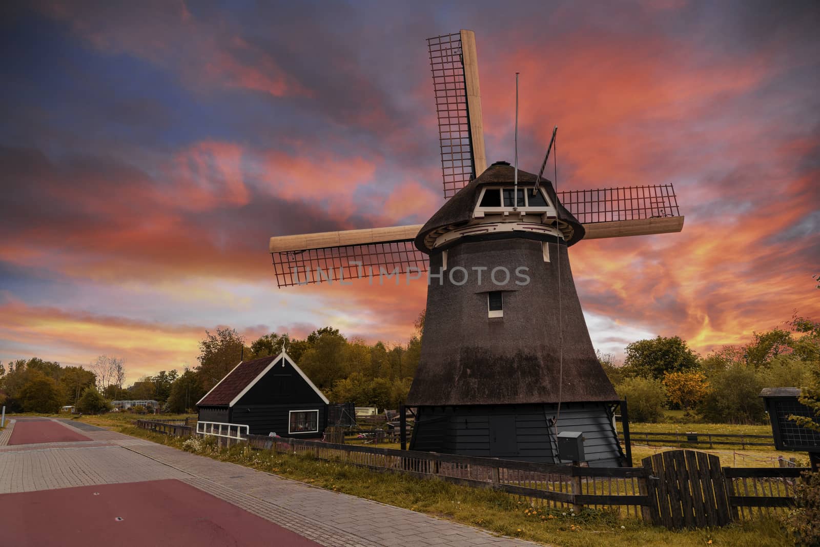 Vivid red and orange color sunset over a Dutch windmill  by ankorlight