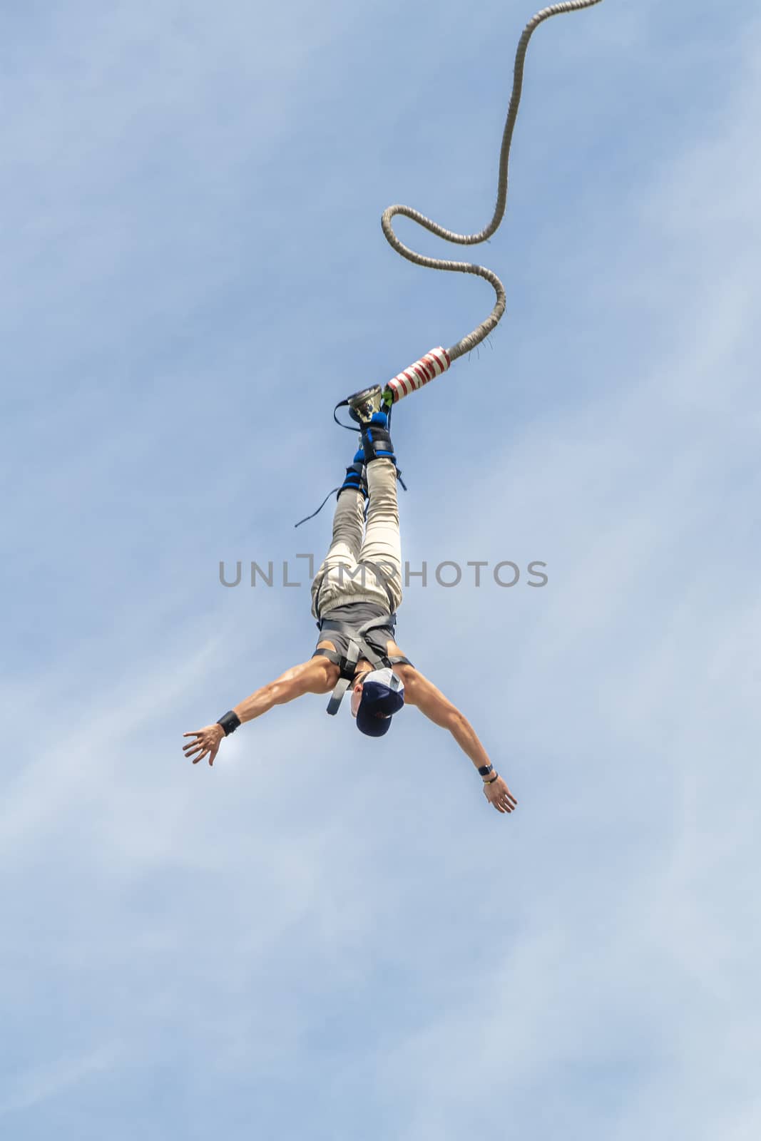 Bungee jumper jump from a platform hanging on the crane into the water against a pur blue spring sky of The Hague, Netherlands