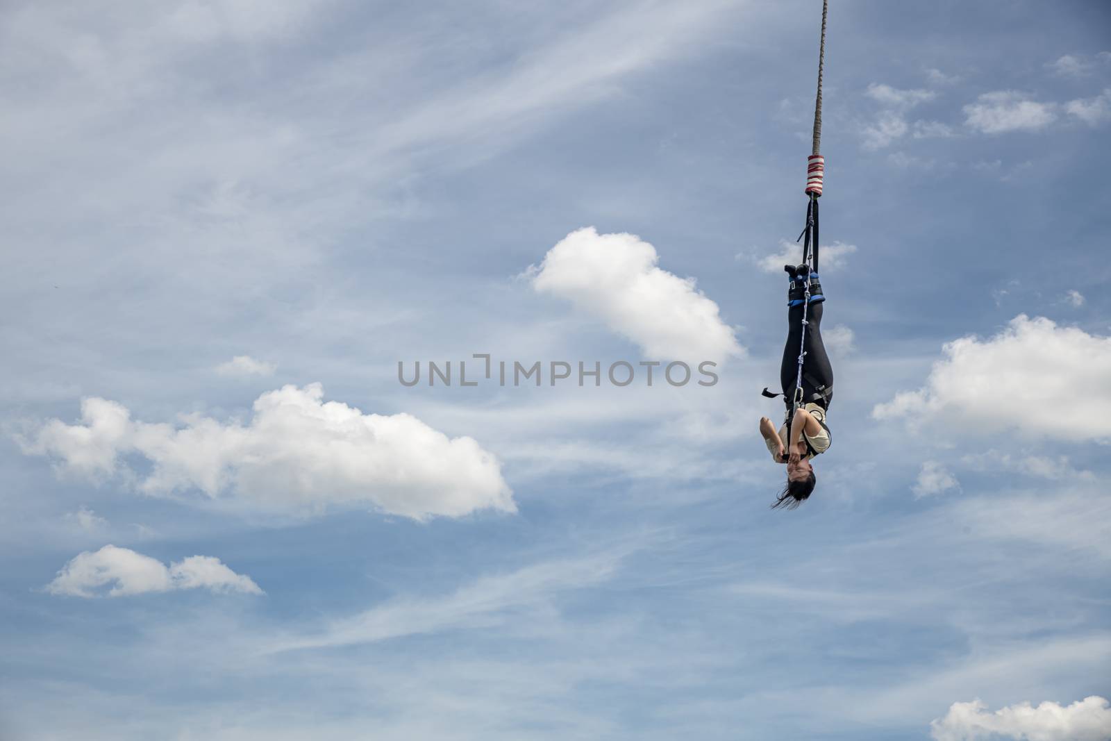 SCHEVENINGEN, 2 June 2019 - Bungee jumper jump from a platform hanging on the crane into the water against a pur blue spring sky of The Hague, Netherlands by ankorlight