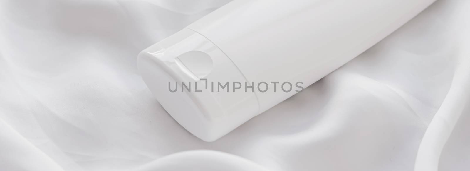 Blank label cosmetic container bottle as product mockup on white silk background, hygiene and healthcare