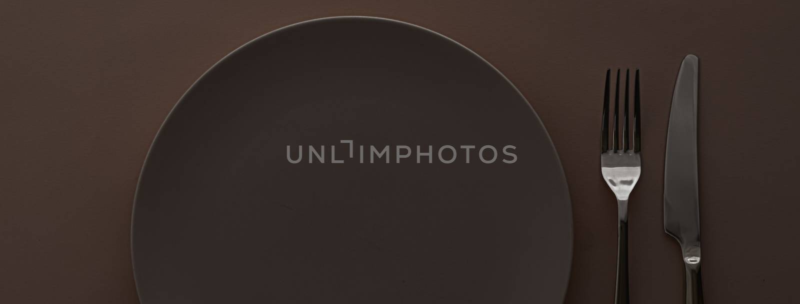 Empty plate and cutlery as mockup set on dark brown background, top tableware for chef table decor and menu branding design