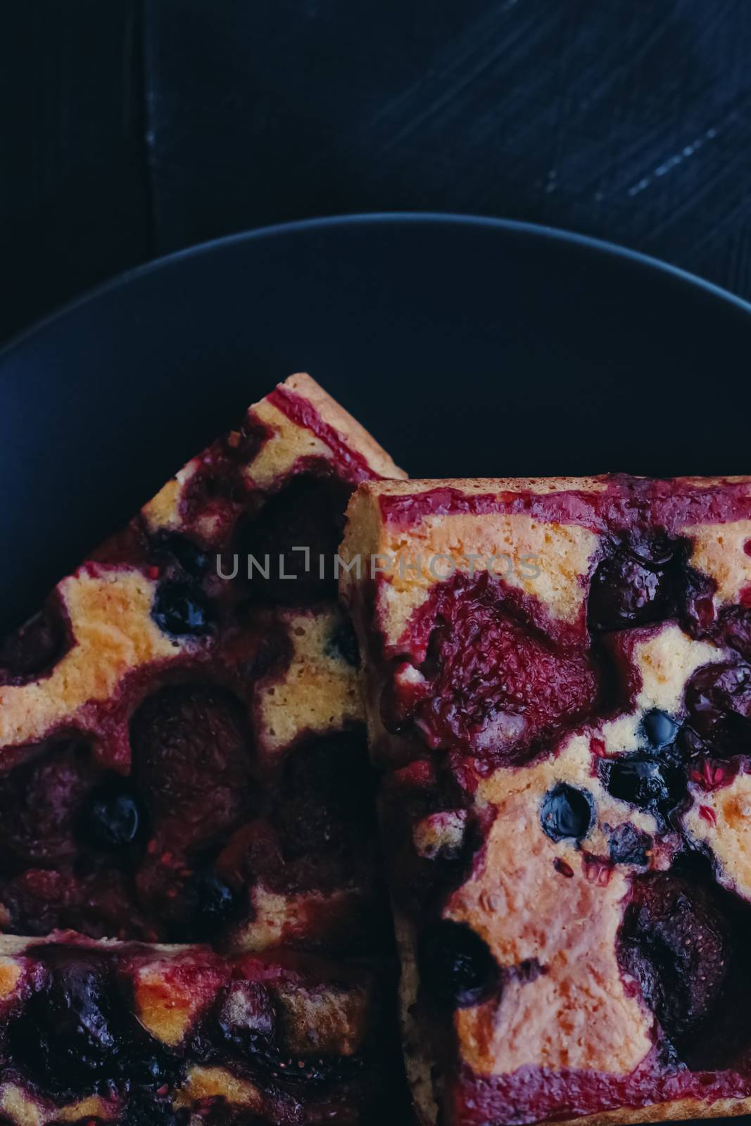 Berry pie on black plate, rustic homemade food with organic ingredients on black background