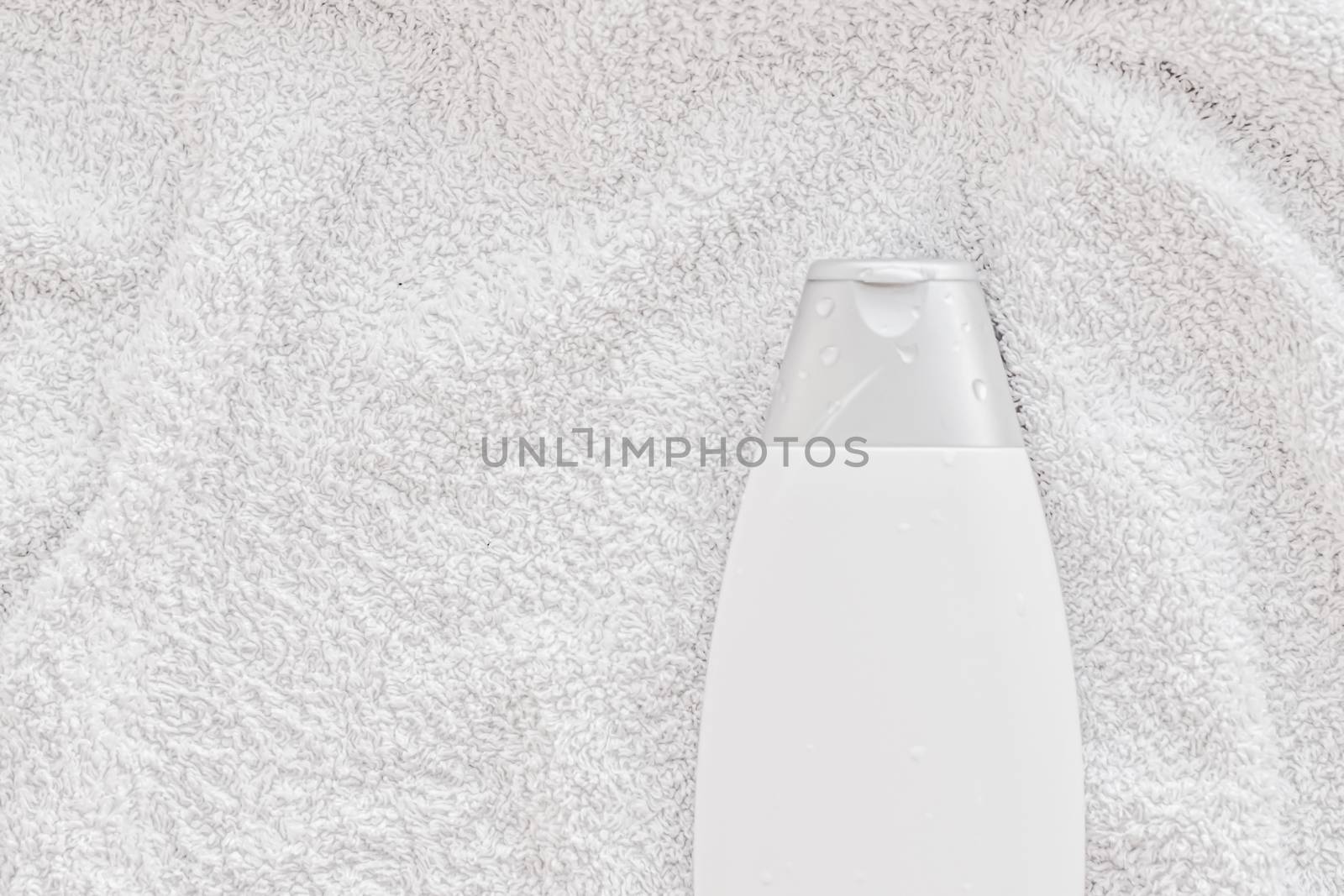 Blank label cosmetic container bottle as product mockup on white towel background, hygiene and healthcare