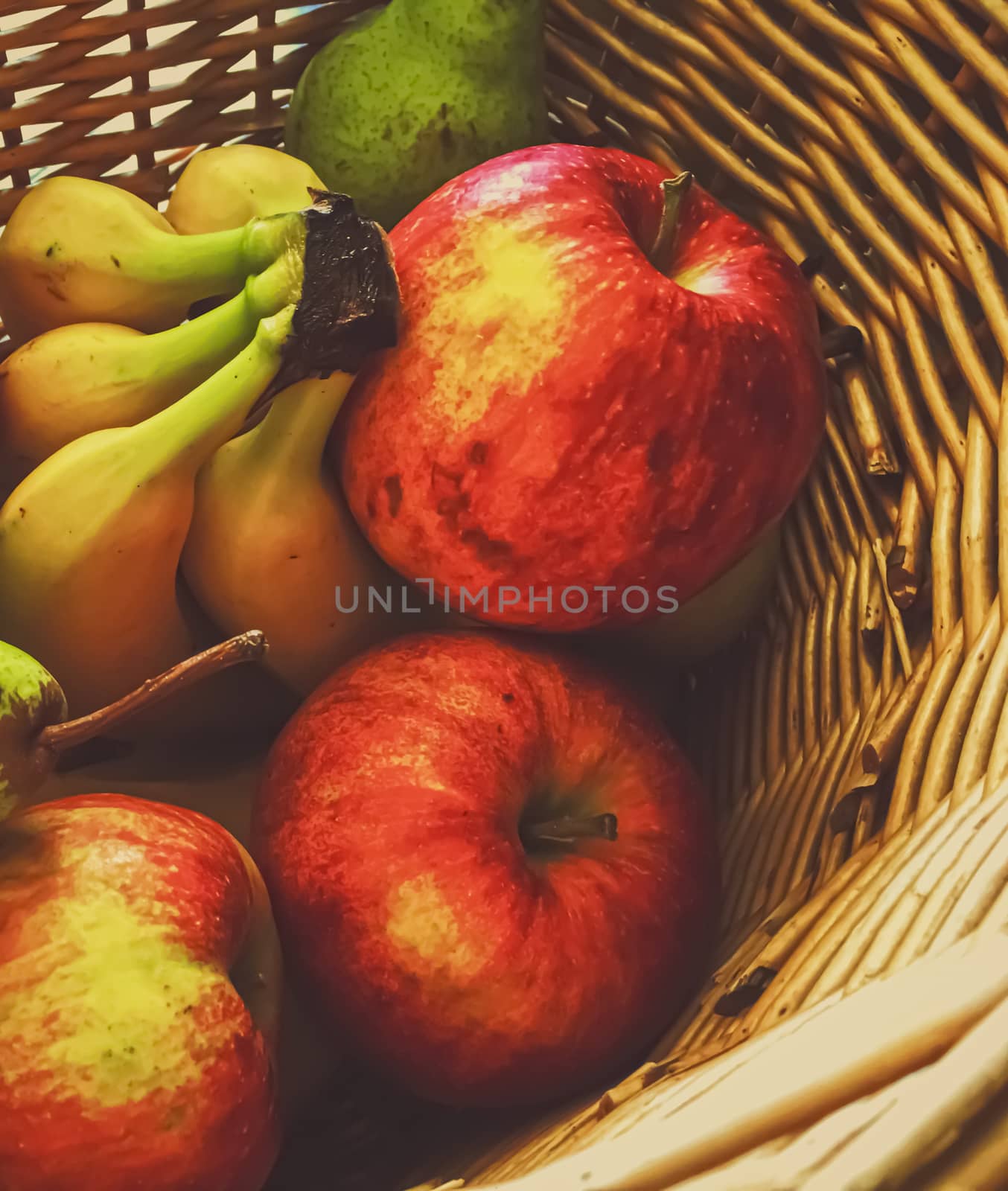 Organic apples, pears and bananas on rustic in a wicker basket, fruits farming and agriculture