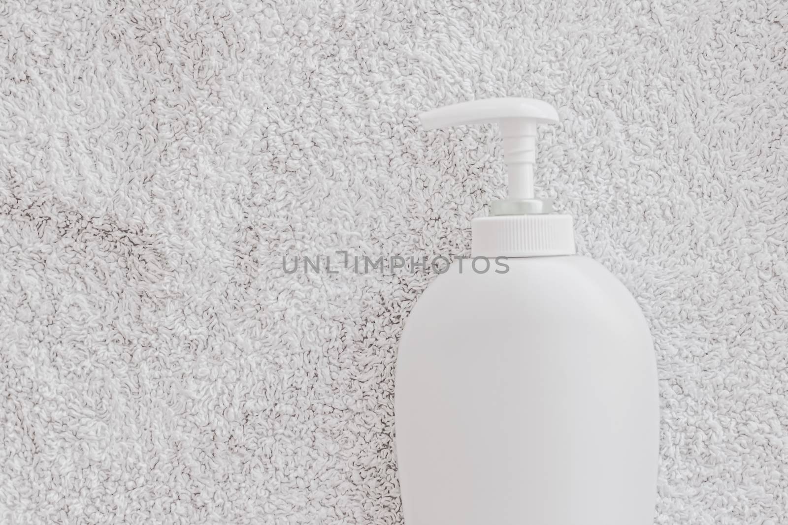 Blank label cosmetic container bottle as product mockup on white towel background by Anneleven