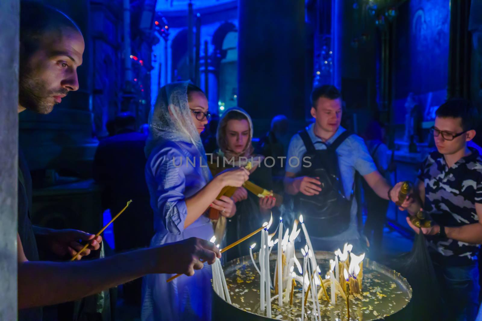 Jerusalem, Israel - April 6, 2018: Orthodox good Friday scene in the church of the holy sepulcher, with pilgrims lighting candles. The old city of Jerusalem, Israel