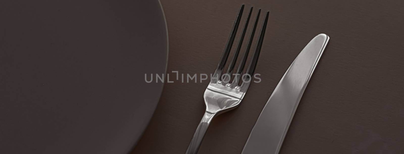 Empty plate and cutlery as mockup set on dark brown background, top tableware for chef table decor and menu branding by Anneleven