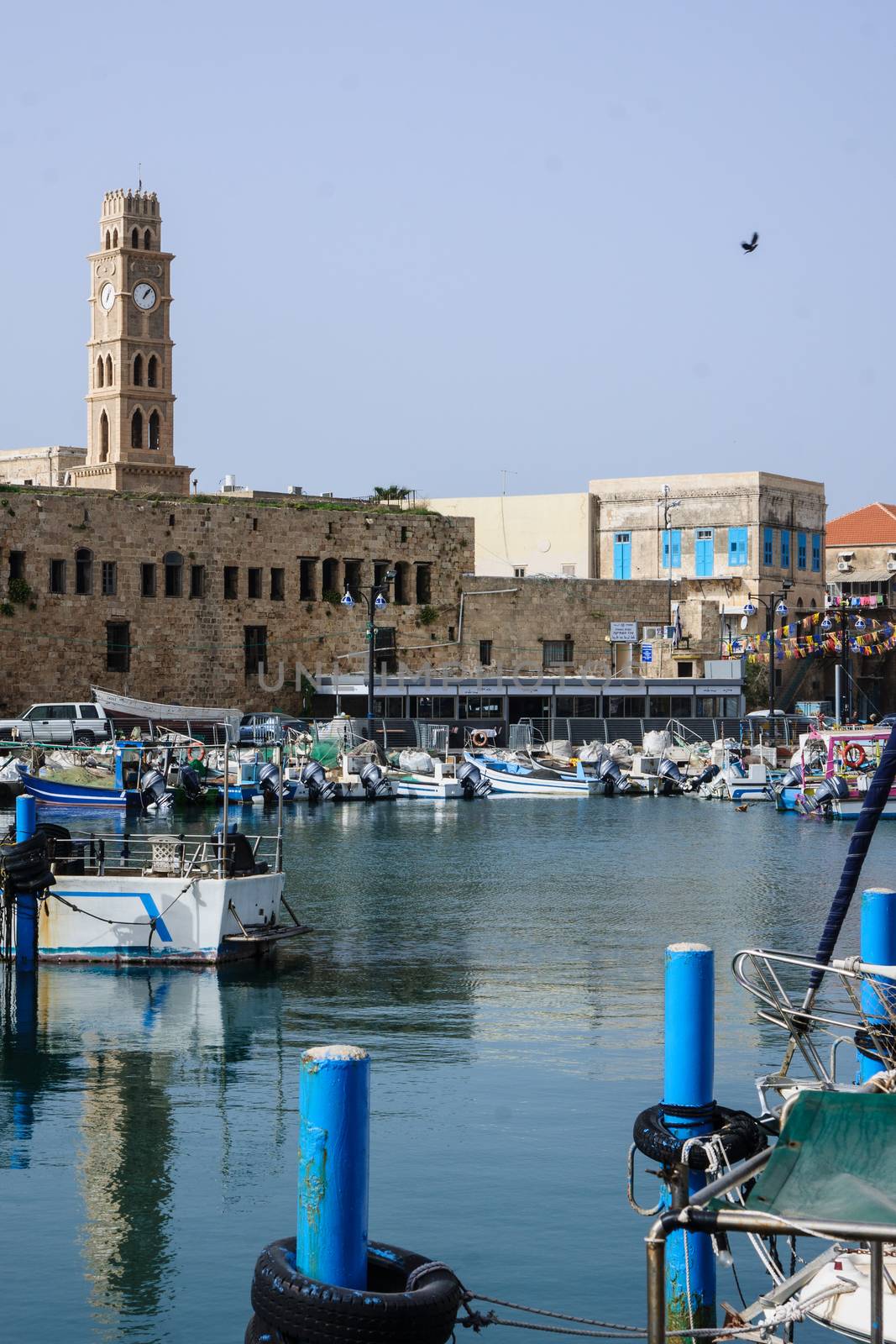 ACRE, ISRAEL - MARCH 06, 2014: Fishing boats, yachts and nearby monuments, in the fishing harbor in the old city of Acre, Israel. Acre is one of the oldest continuously inhabited sites in the world.