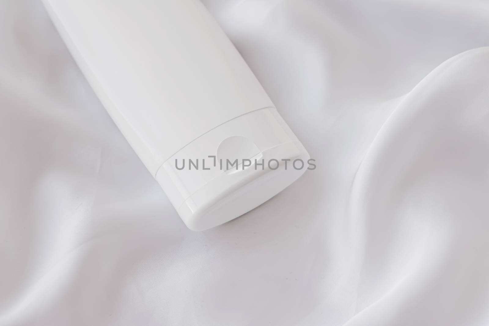 Blank label cosmetic container bottle as product mockup on white silk background by Anneleven