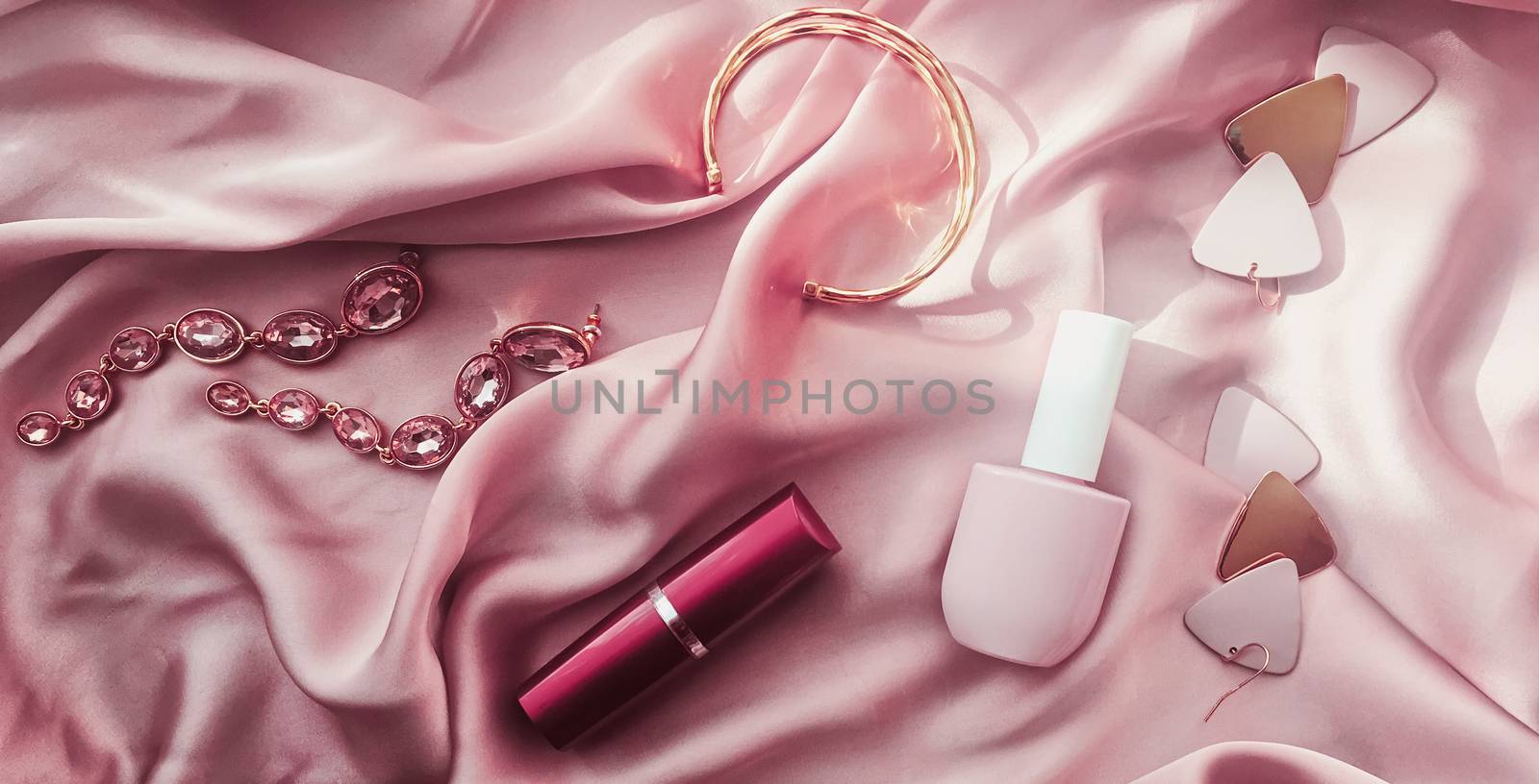 Fashionable and stylish accessories, jewelry and make-up products on pink silk background, beauty and fashion concept