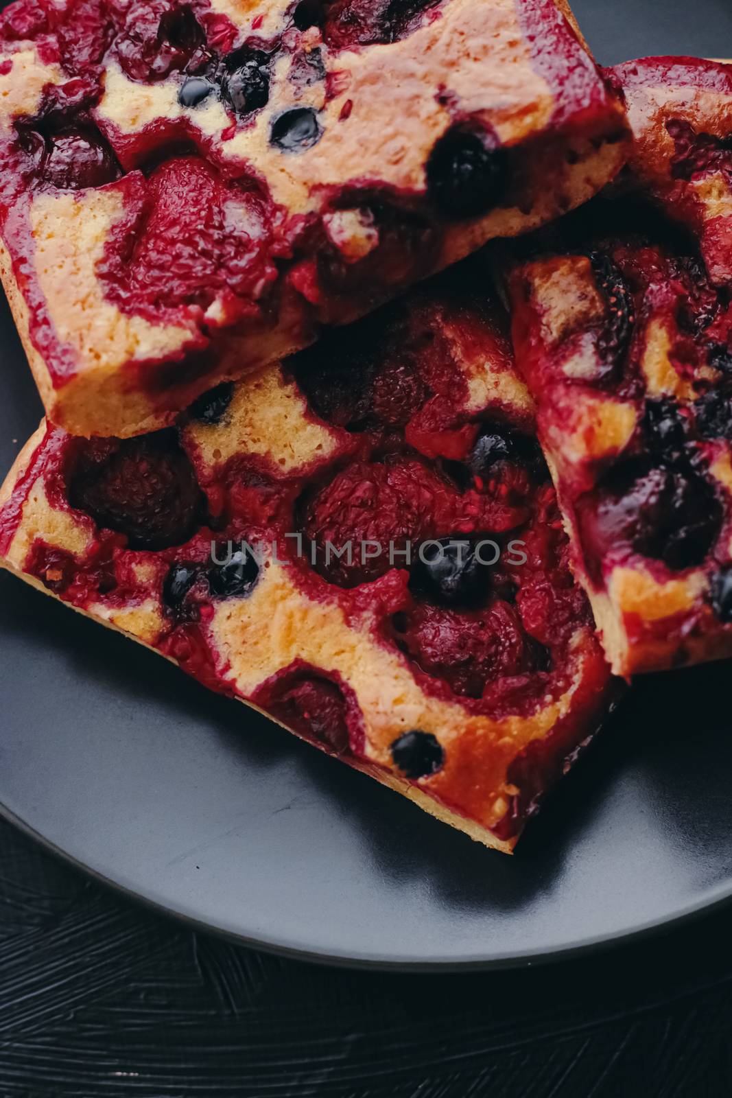 Berry pie on black plate, rustic homemade food with organic ingredients on black background